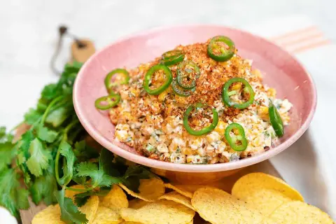 En krämig mexikansk majssallad toppad med jalapeños och serverad med tortillachips och färsk koriander.