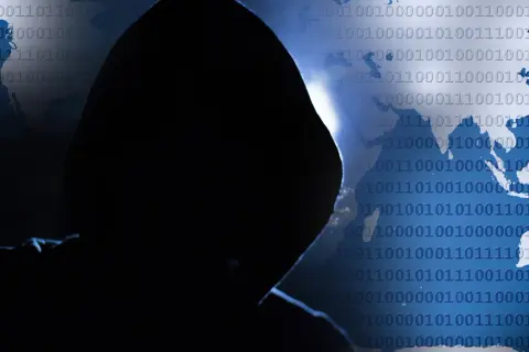 Sylwetka hakera na tle świata i kodu binarnego. Czy wiesz, phishing co to i jak się przed nim chronić?