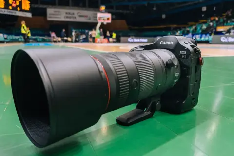 Profesjonalny obiektyw Canon EOS R1 z teleobiektywem 70-200mm na zielonej podłodze hali sportowej.