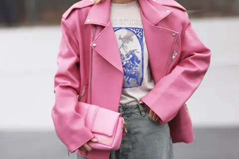 Giacca rosa in ecopelle, che dimostra il suo significato di alternativa sostenibile alla pelle animale. Borsa coordinata e jeans.