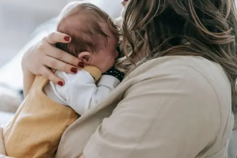 Matka tuli dziecko, które może mieć zespół Sandifera. Delikatne objęcia i troska.