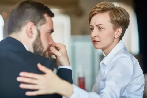 Donna consola uomo in lutto, offrendo supporto. Potrebbe essere un permesso per lutto.