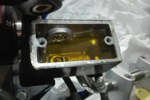 Zbiorniczek płynu hamulcowego w motocyklu z żółtym płynem.