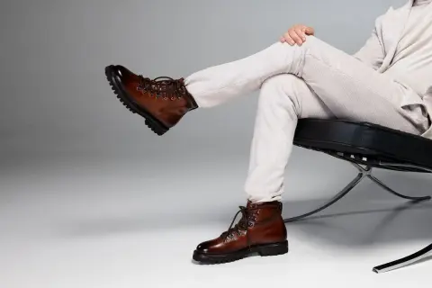 Un uomo con un outfit elegante, composto da pantaloni a coste e giacca chiara, sfoggia un paio di chelsea boots uomo in pelle marrone lucida, perfetti per un look sofisticato.