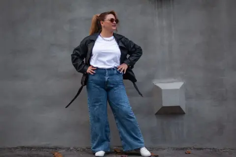 Kobieta w skórzanej kurtce i jeansach z wysokim stanem, idealnych dla puszystych. Stylowy look na co dzień.