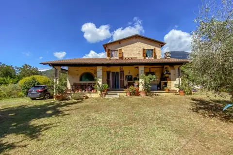 Una casa di campagna con un'auto parcheggiata, piante in vaso e un prato verde. Il momento perfetto quando comprare casa.