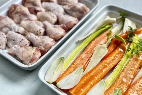 Przygotowania do pieczonego rosołu z warzyw: kurczak i warzywa korzeniowe, pory, cykoria.