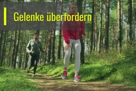 Zwei Läufer im Wald. Eine Frau hält sich das Knie, während ein Mann hinter ihr joggt. Die Frage ist, ob joggen gesund ist, wenn man die Gelenke überfordert.
