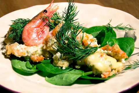 En krämig räkröra med dill, serverad på färsk spenat. Perfekt som sallad till pajen.