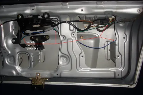 Wnętrze drzwi samochodu z widocznym siłownikiem centralnego zamka i okablowaniem.
