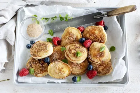 Små, gyllene krabbelurer, strösslade med socker och kanel, serveras med färska bär. Ett enkelt krabbelurer recept för fika.