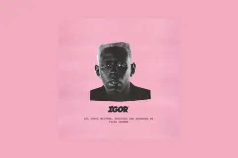 Okładka albumu "IGOR" Tylera, The Creatora. Czarno-białe zdjęcie artysty na różowym tle.