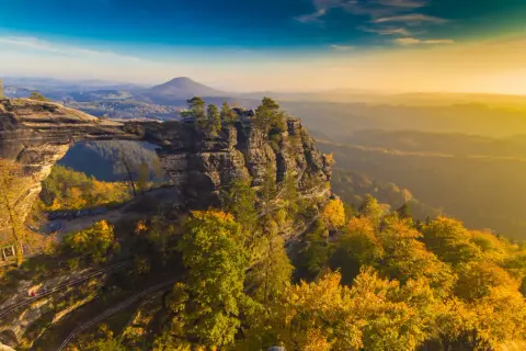 Skalny most Pravčická brána w Czechach, idealne miejsce na weekendowy wypad. Jesienne kolory lasów i zachodzące słońce tworzą magiczny widok.