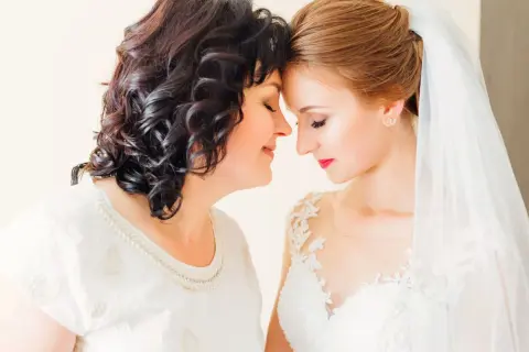Mama i córka, obie elegancko na ślub córki, dzielą wzruszającą chwilę.