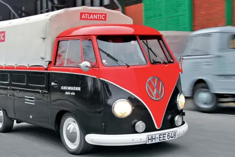 Klasyczny vw t1 w dwukolorowym malowaniu, z plandeką z logo "Atlantic", przemierza drogę.