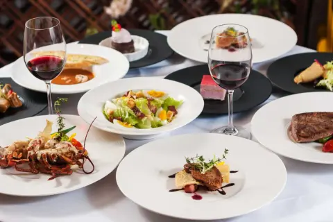 Elegancka kolacja w stylu kuchnia francuska: homar, stek, sałatka Cezar, desery i czerwone wino.