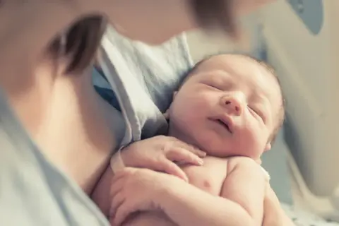 Delikatne objęcie noworodka, który śpi spokojnie, gdy zarasta ciemiączko.
