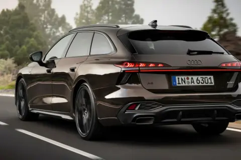 Elegancki Audi Avant w brązowym kolorze jedzie po krętej drodze wśród drzew.