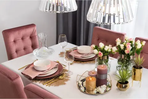 Elegancko nakryty stół z różowymi krzesłami, kwiatami i świecami. Jak ułożyć tiul na stole, by stworzyć taką atmosferę?