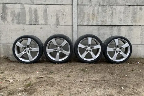 Cztery aluminiowe felgi z oponami Camaro SS na tle betonowego muru.