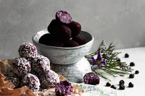 Läckra chokladbollar recept med blåbär och kokos. En skål med mörka bollar och en hög med kokosbollar.