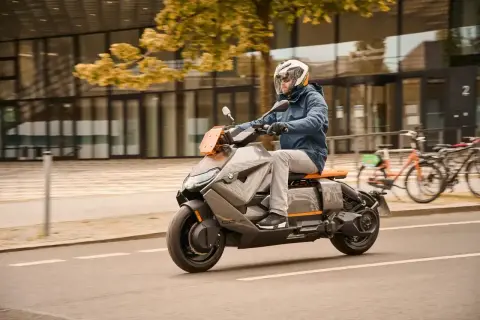 Mężczyzna w kasku jedzie na futurystycznym skuterze BMW CE04 po mieście.