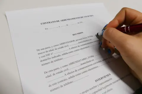 Mano con bolígrafo firmando un contrato de arrendamiento de vivienda. Se detallan los requisitos para alquilar un piso como propietario.