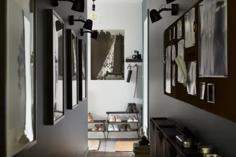 En avlång hall med inspiration från stadsliv. Tavlor, skohyllor och en anslagstavla skapar en funktionell och stilfull entré.