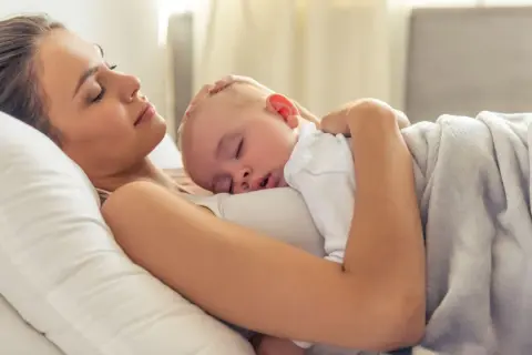 Mama i dziecko śpią wtuleni w siebie. To piękny moment kangurowania, pełen miłości i spokoju.