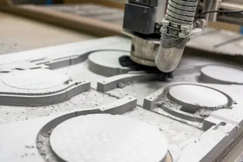 Frezowanie CNC tworzy precyzyjne kształty w materiale. Maszyna usuwa nadmiar, tworząc wgłębienia i kontury.