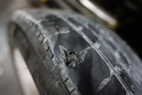 Gros plan sur une hernie sur un pneu de voiture, montrant le caoutchouc déchiré et usé. Un danger potentiel sur la route.