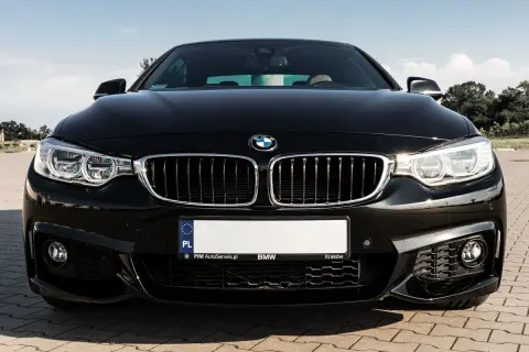 Czarny BMW F32 435i z błyszczącą atrapą chłodnicy i ostrymi reflektorami, gotowy do jazdy po krakowskich ulicach.