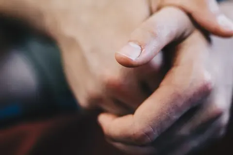 Zbliżenie na dłonie, palec wskazujący z czystym paznokciem, jakby szukał czegoś w piasku z **krzem**u.