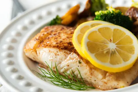 Pieczony halibut z cytryną i koperkiem, podany z pieczonymi ziemniakami i brokułami. Zdrowy posiłek, który nie przekracza halibut kcal.