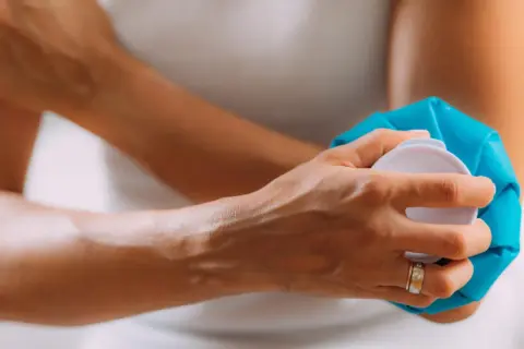 Une personne applique une poche de glace sur son bras, peut-être une conséquence d'une prise de sang mal faite.