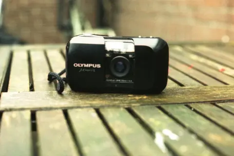 Olympus mju-1 camera, a classic choice for the best film for Olympus Stylus, rests on a weathered wooden surface.