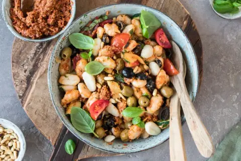 Gnocchi-Salat mit Pesto, Tomaten, Oliven und Pinienkernen in einer Schüssel.