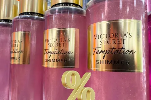 Różowe mgiełki Victoria's Secret Temptation Shimmer z złotymi etykietami i złotym symbolem procentu.