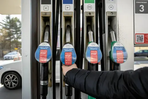 Ręka sięga po dystrybutor paliwa. Wykres cen paliw w Polsce 10 lat pokazuje zmienność kosztów.