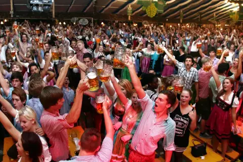 Menschen jubeln und stoßen mit Bierkrügen an auf dem Volksfest Freising.