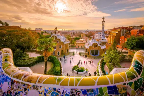 Park Güell w Barcelonie, jednym z największych miast Hiszpanii, zachwyca mozaikową ławką i bajkowymi budynkami o zachodzie słońca.