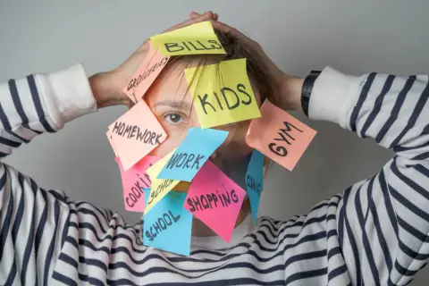 Una persona abrumada por tareas: "Bills", "Kids", "Homework", "Work", "Gym", "Shopping". ¿Cómo ser mejor persona? Prioriza y respira.
