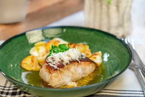 En lyxig torskrygg med krispiga potatisar, toppad med riven ost och färska örter. Ett perfekt lyxigt torskrygg recept för en fin middag.