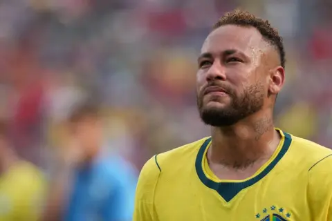 Neymar, w wieku 31 lat, w żółtej koszulce reprezentacji Brazylii, zamyślony na boisku.