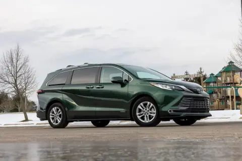 Zielona Toyota Sienna zaparkowana obok placu zabaw.