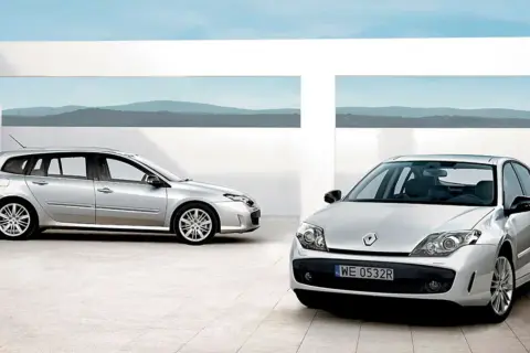 Dwa srebrne Renault Laguna 3 2.0 dCi: kombi i sedan, stojące na nowoczesnym placu z widokiem na góry.