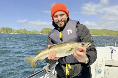 Glücklicher Angler mit frisch gefangenem Fisch vor der Küste von Farsund. Ein perfekter Tag für Angeln Hotspots!