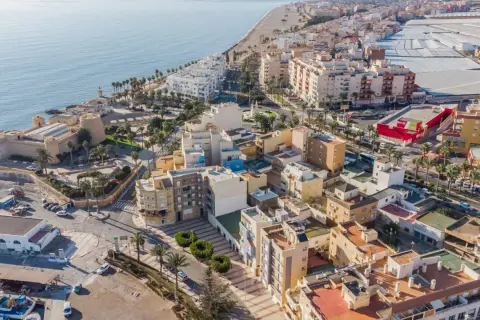 Vista aérea del **centro de Roquetas de Mar**, con el castillo, la playa, edificios residenciales y el mar Mediterráneo.