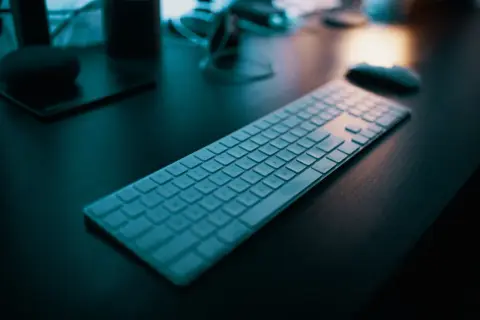 Klawiatura na biurku, gotowa do pracy. Dowiedz się, jak napisać ź na laptopie, by ułatwić sobie pisanie.