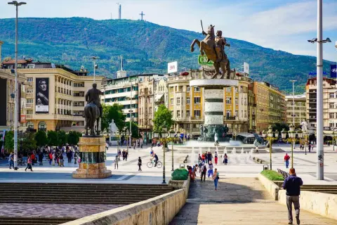 Pomnik wojownika na koniu na placu w Skopje, Macedonia Północna, z górami w tle.